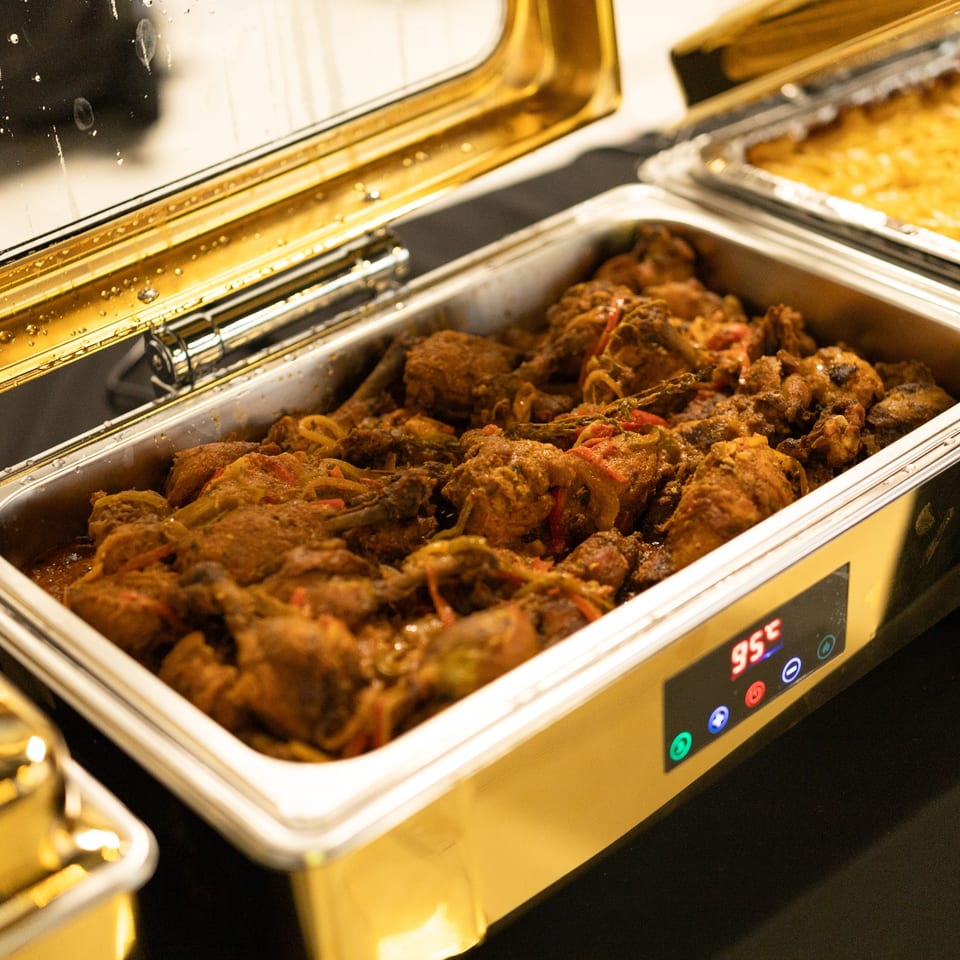 Stewed chicken and mac and cheese in catering trays